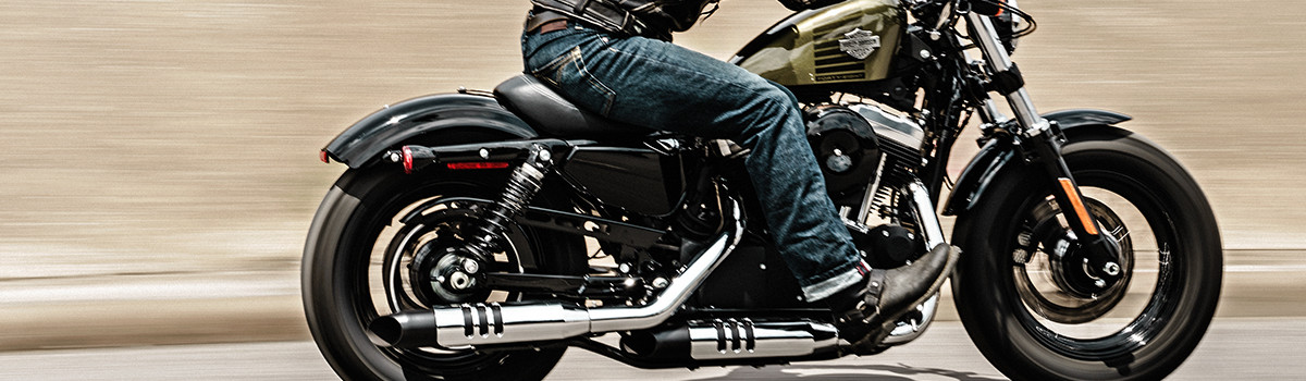 Man riding a black Harley-Davidson® motorcycle on an open street